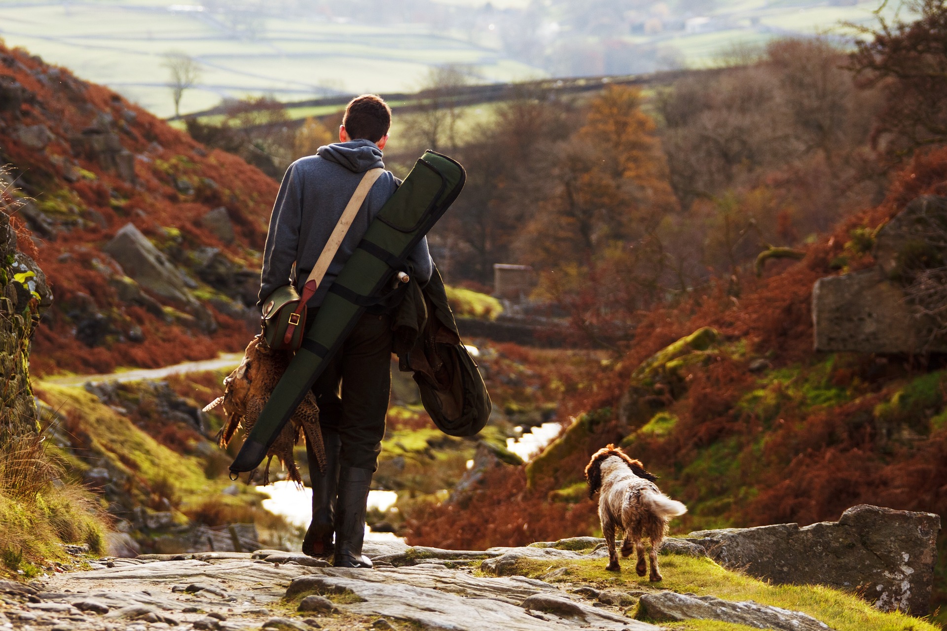 A man walking with his dog holding a turkey and an air gun in a case